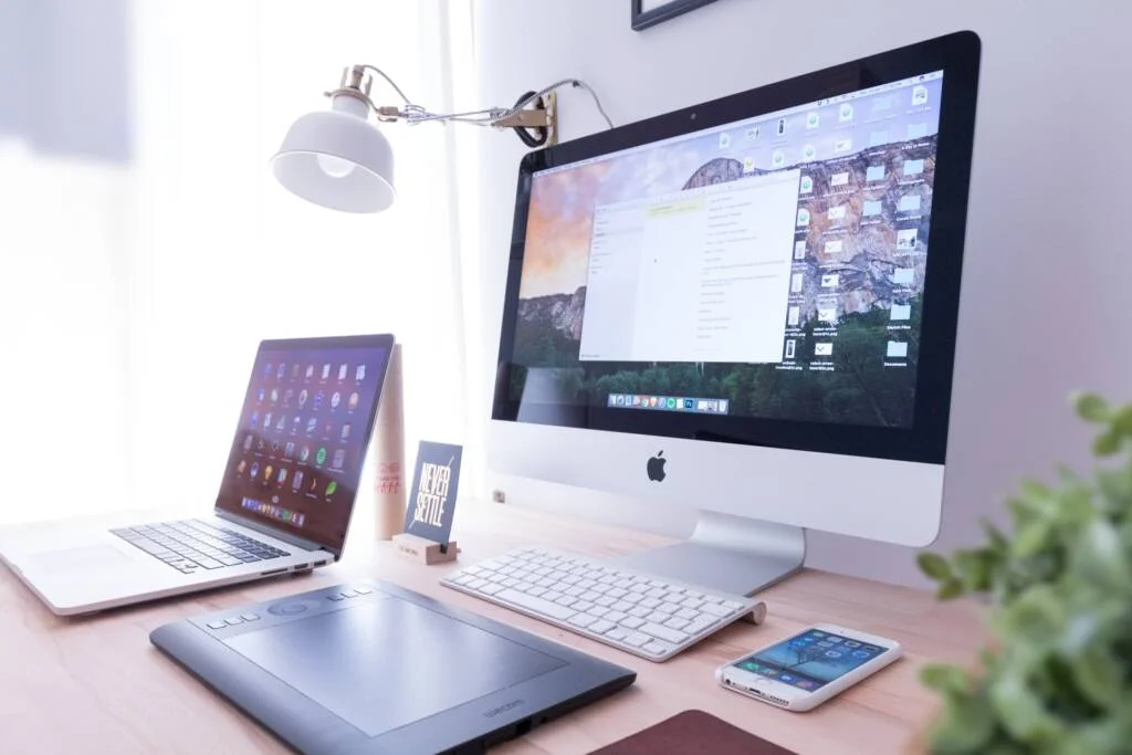 A computer, tablet, and phone on a table.