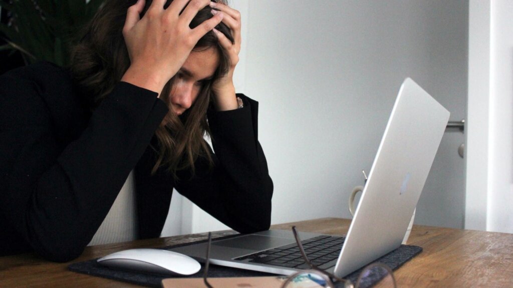 7 Time Management and Productivity Tips for Web Designers 2 A frustrated web designer clambering her head over her laptop.