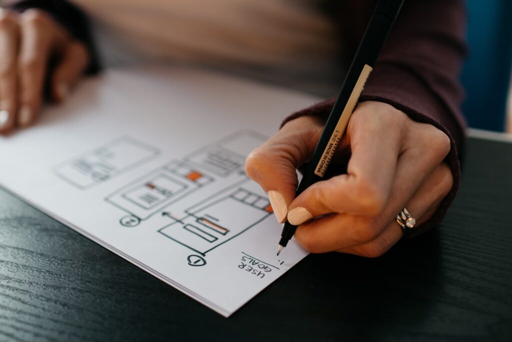 A web designer working on a website template on paper, focusing on using visual elements to boost website conversions by catering to user goals.